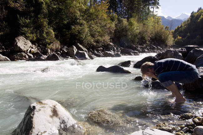 Homme randonneur se lavant le visage dans la rivière, Lauterbrunnen, Grindelwald, Suisse — Photo de stock