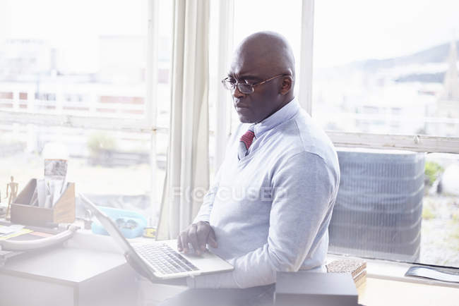 Зрелый мужчина в очках в офисе с помощью ноутбука — стоковое фото