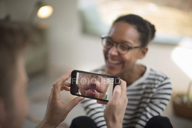 Person holding smartphone and woman laughing at home — Stock Photo