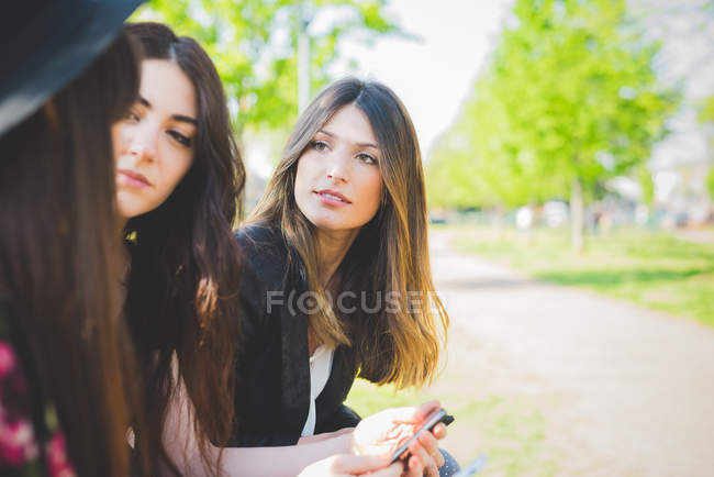 Três jovens amigas conversando no parque — Fotografia de Stock