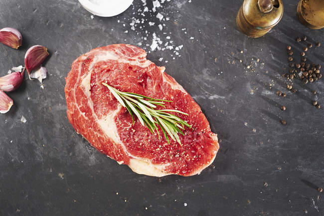 Uncooked sirloin steak with rosemary, garlic and salt — Stock Photo