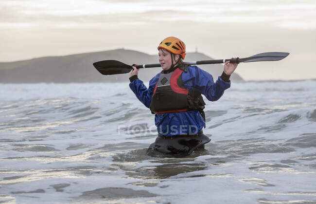 Mulher usando capacete segurando remo no mar — Fotografia de Stock