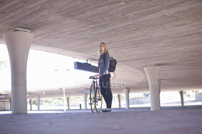 Giovane donna in attesa con la bicicletta in città sottopassaggio — Foto stock