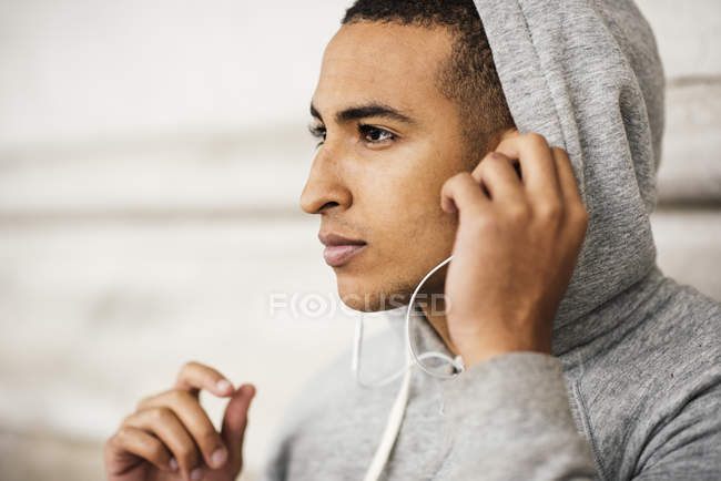 Corredor masculino con capucha gris escuchando música de auriculares - foto de stock