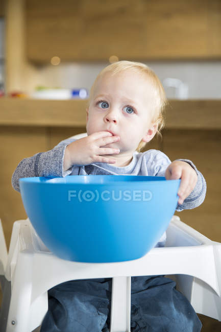Male toddler snacking from large bowl on high chair — Stock Photo