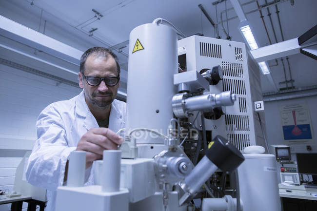 Лаборант, работающий над профессиональным микроскопом — стоковое фото