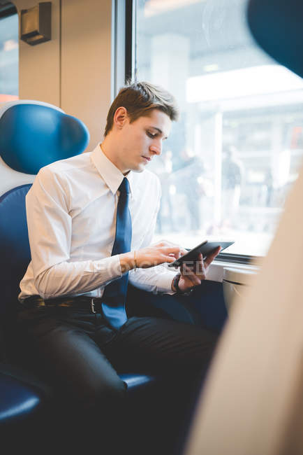 Retrato de jovem empresário viajante usando tablet digital no trem . — Fotografia de Stock