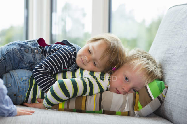 Portrait of tired boy and female toddler lying on sofa — Stock Photo