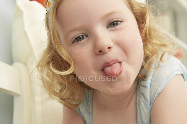 Retrato de menina deitada no assento furando a língua para fora — Fotografia de Stock