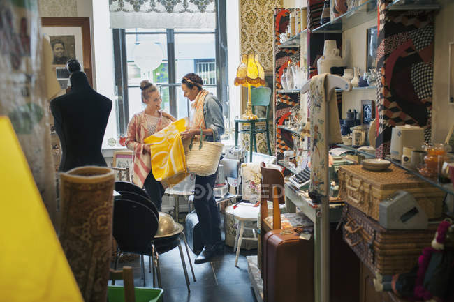 Jovem cliente feminino olhando para cobertor amarelo na loja vintage — Fotografia de Stock