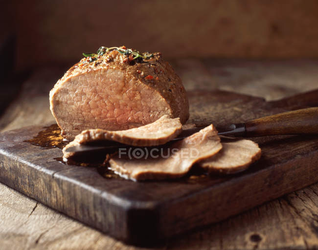 Carne assada fatiada em tábua de corte de madeira rústica — Fotografia de Stock