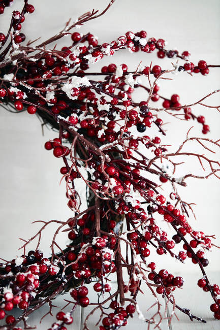 Colpo ritagliato di ghirlanda di Natale di ramoscelli e bacche rosse — Foto stock