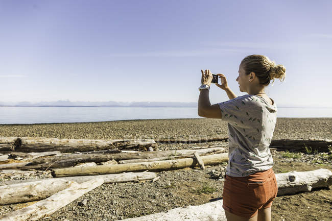Mulher fotografando em Miracle Beach Provincial Park, Vancouver Island, British Columbia, Canadá — Fotografia de Stock
