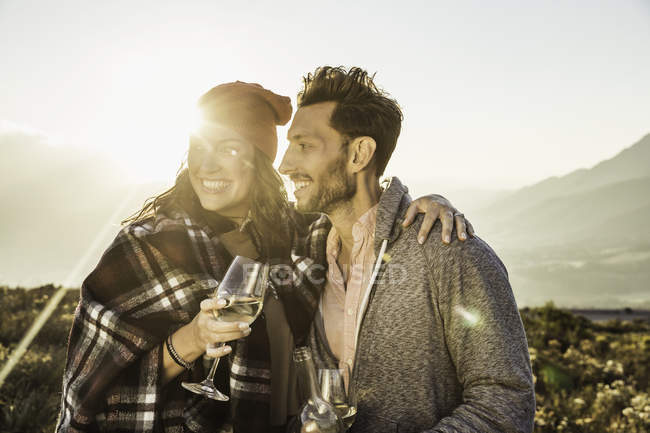 Couple dans le champ tenant des verres à vin regardant loin — Photo de stock