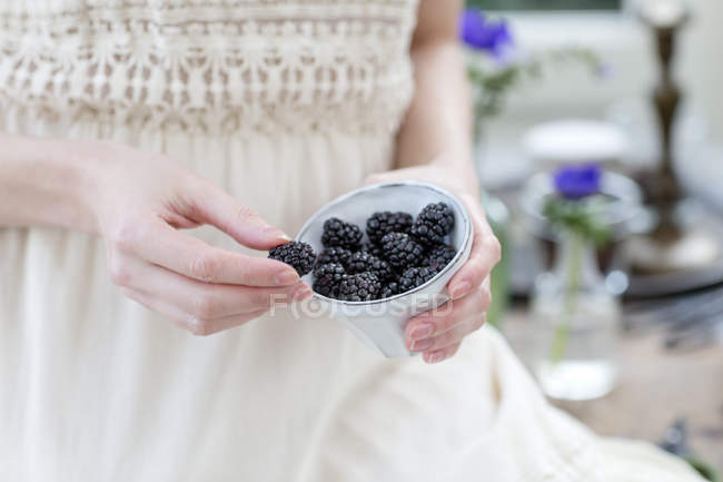 Cropped view of woman holding bowl of blackberries — Stock Photo