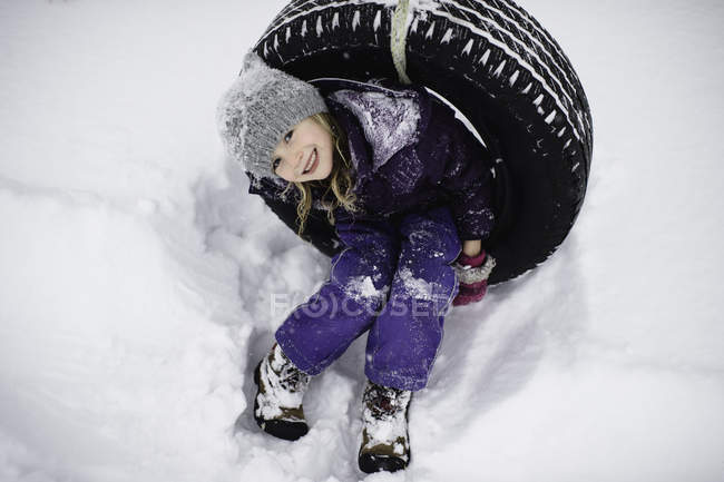 Overhead ritratto di ragazza su pneumatico swing in neve — Foto stock