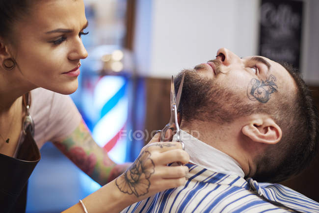 Hairdresser trimming customer's beard — Stock Photo
