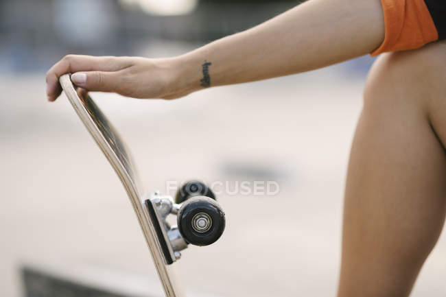 Tiro cortado de skate fêmea segurando skate — Fotografia de Stock