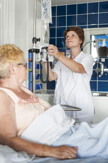 Nurse helping patient in hospital bed — Stock Photo