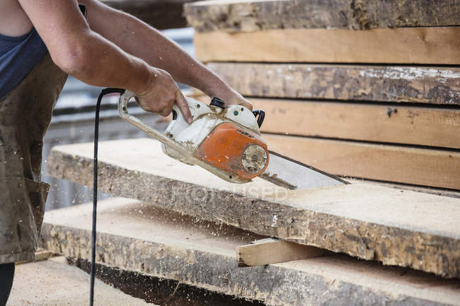 Carpenter sawing wooden plank — Stock Photo