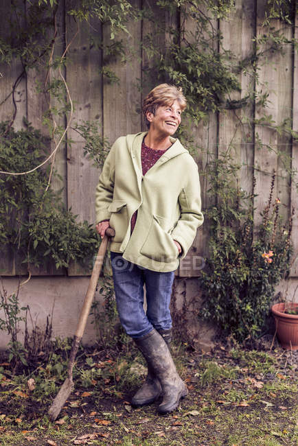 Портрет зрелой женщины, опирающейся на лопату в саду — стоковое фото