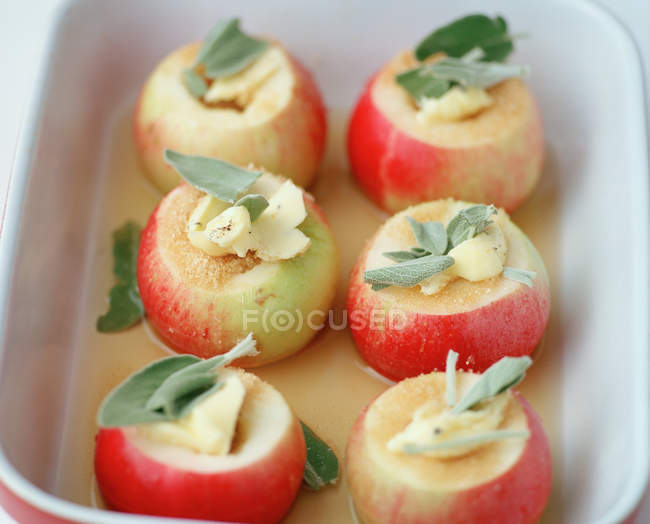 Apples stuffed with butter, sugar and sage in baking dish — Stock Photo