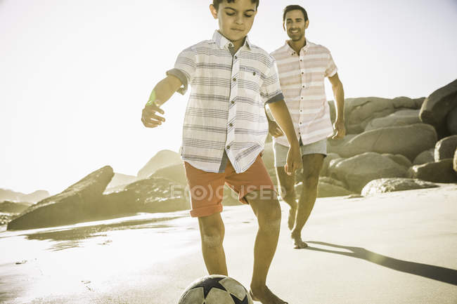 Отец и сын играют в футбол на пляже — стоковое фото