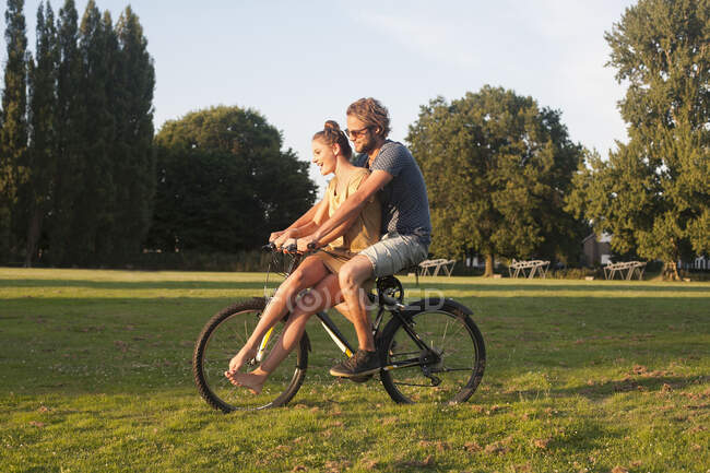 Romantique jeune couple à vélo ensemble dans le parc — Photo de stock