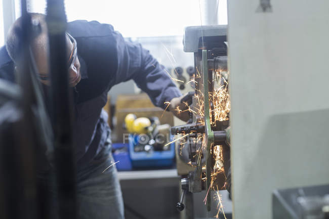 Kaukasischer Erwachsener überwacht Schleifmaschine in Werkstatt — Stockfoto