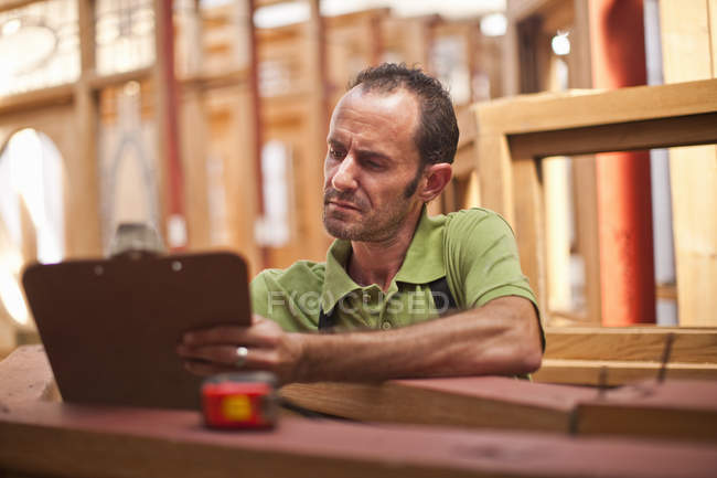 Carpenter writing on clipboard — Stock Photo