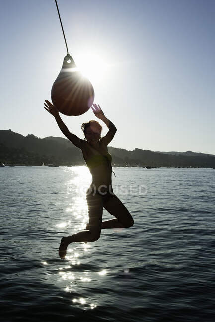 Young woman swinging from boat fender, Sausalito, California, USA — Stock Photo