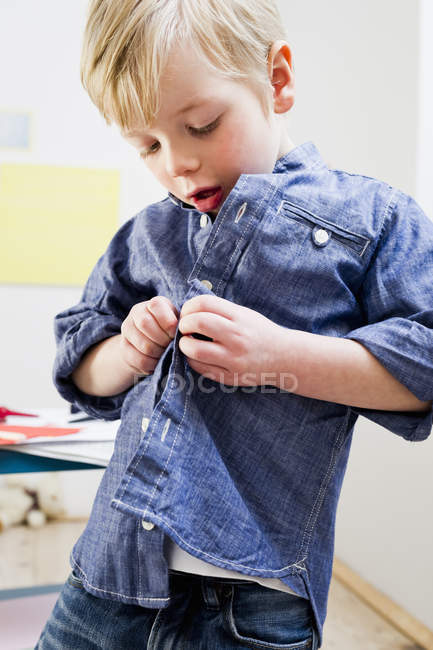 Boy buttoning shirt at home — Stock Photo