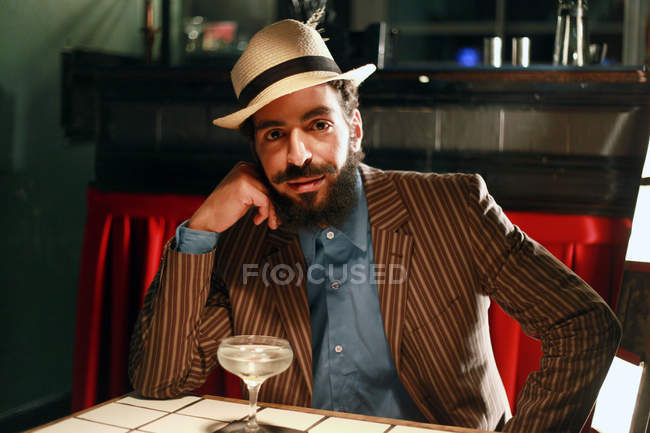 Uomo con cocktail seduto al bar e guardando nella fotocamera — Foto stock