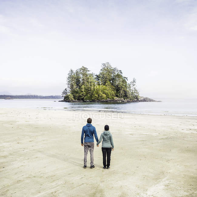 Couple looking out at island from Long Beach, Pacific Rim National Park, Vancouver Island, British Columbia, Canada — Stock Photo
