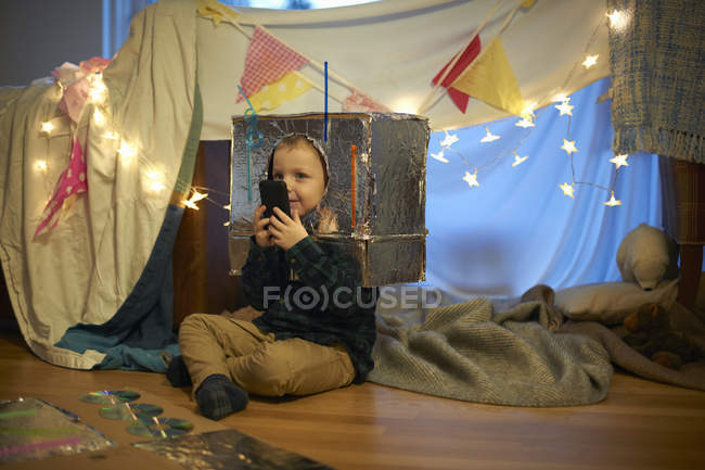 Boy in robot costume looking at smartphone — Stock Photo