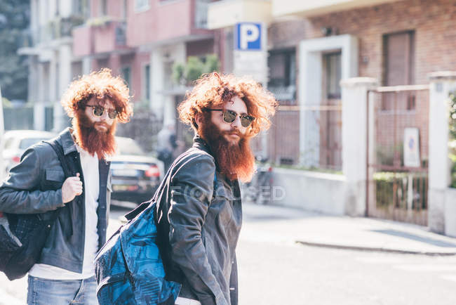 Giovane maschio hipster gemelli con i capelli rossi e la barba passeggiare su strada — Foto stock