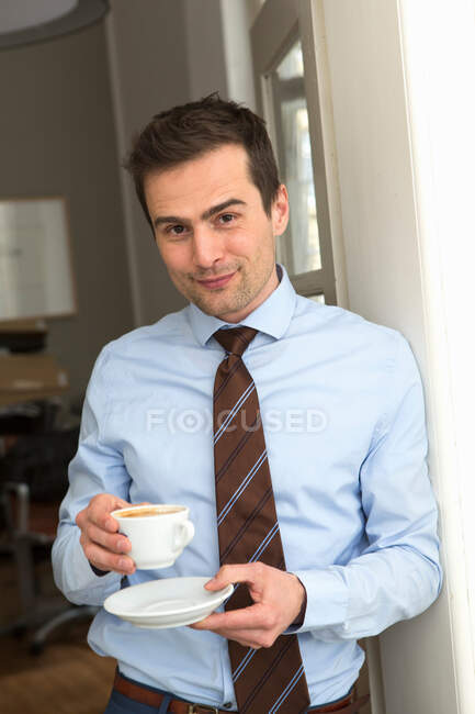 Maduro homem vestindo camisa e gravata segurando xícara de café — Fotografia de Stock