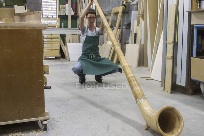 Mujer en taller chequeando alphorn - foto de stock