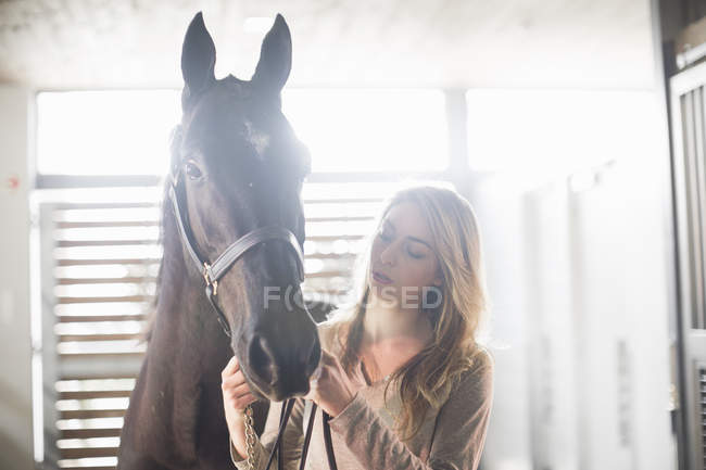 Portrait of young woman with black horse — Stock Photo