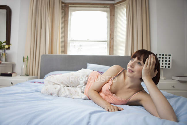 Молодая женщина, лежащая на кровати в мечтах — стоковое фото