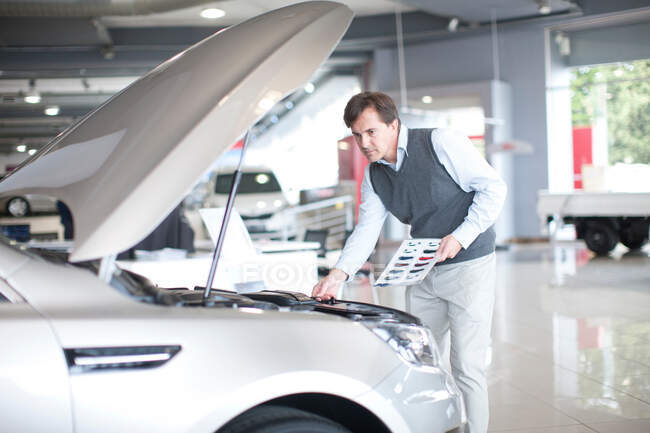 Mid adult man checking car bonnet in showroom — Stock Photo