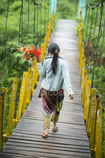 Junge Frau auf Fußgängerbrücke mit Blumen, shan state, keng tung, burma — Stockfoto