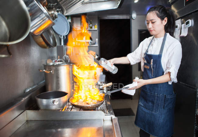 Asiatico femmina chef flambeing in commerciale cucina — Foto stock