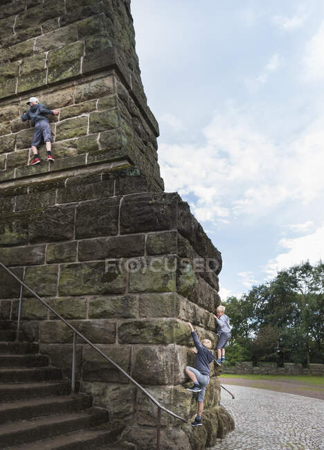 Boys climbing stone wall — Stock Photo