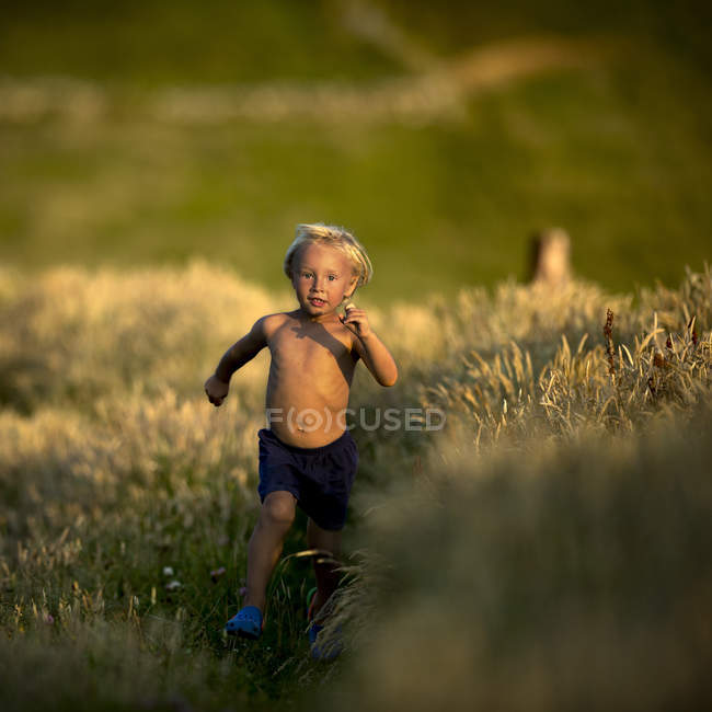 Young boy running through field — Stock Photo