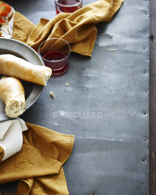 Draufsicht auf rustikalen Metalltisch mit Teller mit frischem Brot und Rotwein — Stockfoto