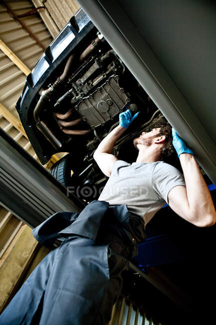Männlicher Mechaniker überprüft Motor des Autos unten — Stockfoto