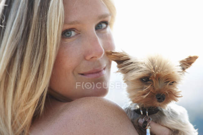 Mature woman holding pet dog, looking over shoulder — Stock Photo