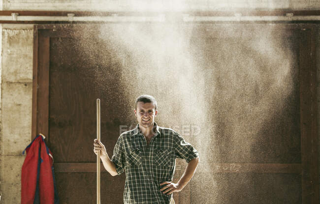 Portrait of young male farmworker in dusty farm barn — Stock Photo