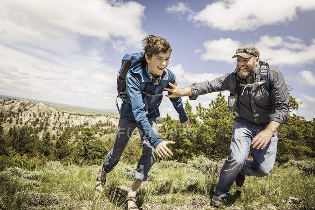 Father and teenage son chasing each other on hiking trip, Cody, Wyoming, USA — Stock Photo